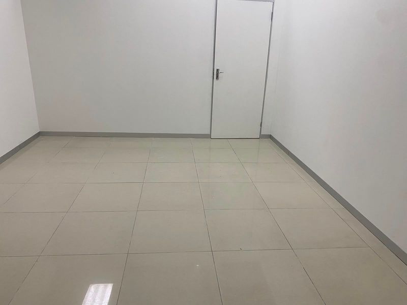 A clean, empty commercial office space featuring neutral tiled flooring and white walls, suitable for a variety of business configurations.