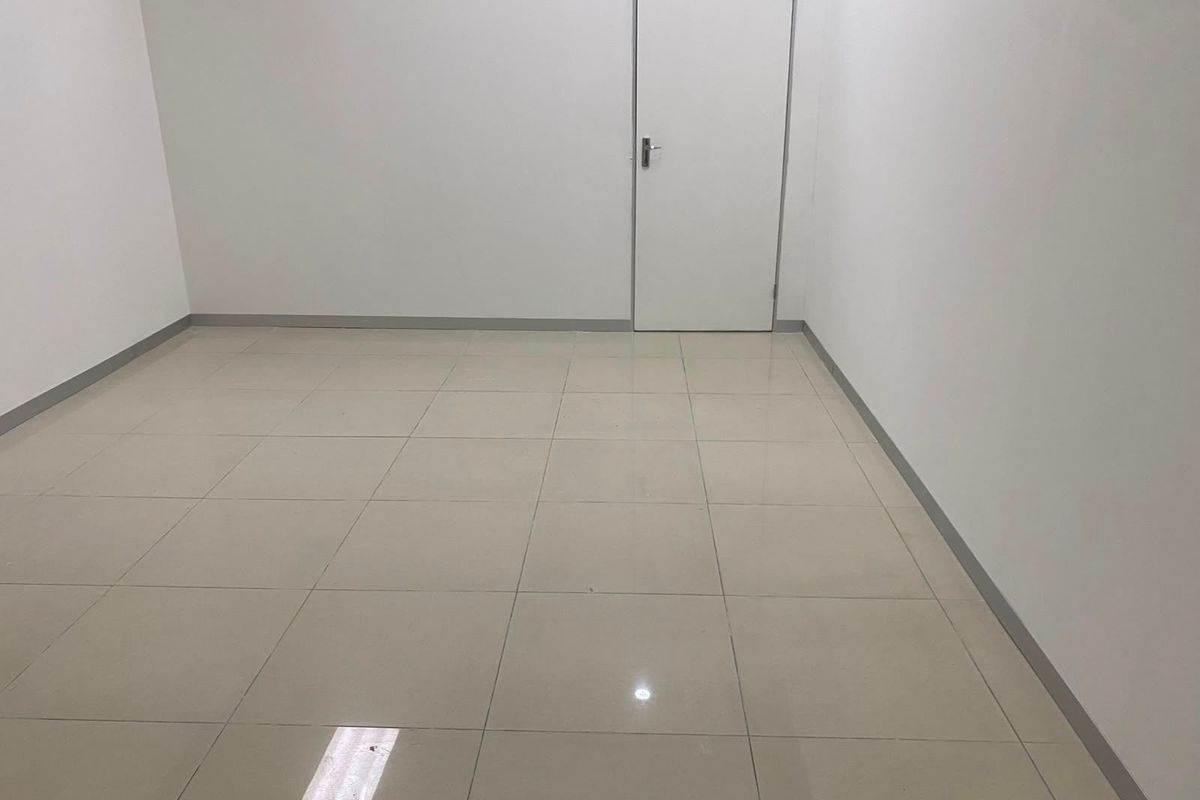 A clean, vacant office space featuring neutral ceramic floor tiles and a simple interior door, ready for commercial fit-out.