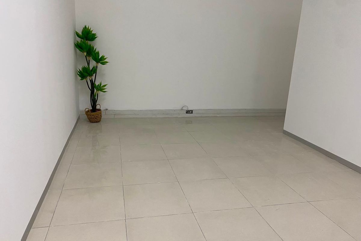 A clean, empty commercial office space featuring neutral tiled flooring and white walls, suitable for a variety of business configurations.