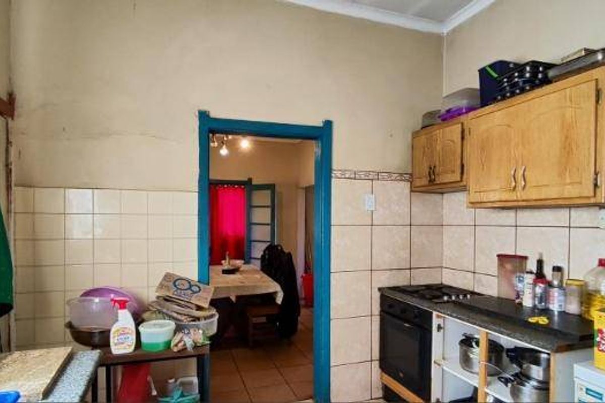 A dated kitchen featuring built-in wooden cabinetry, tiled splashbacks, and a built-in oven, offering potential for modernization and renovation.