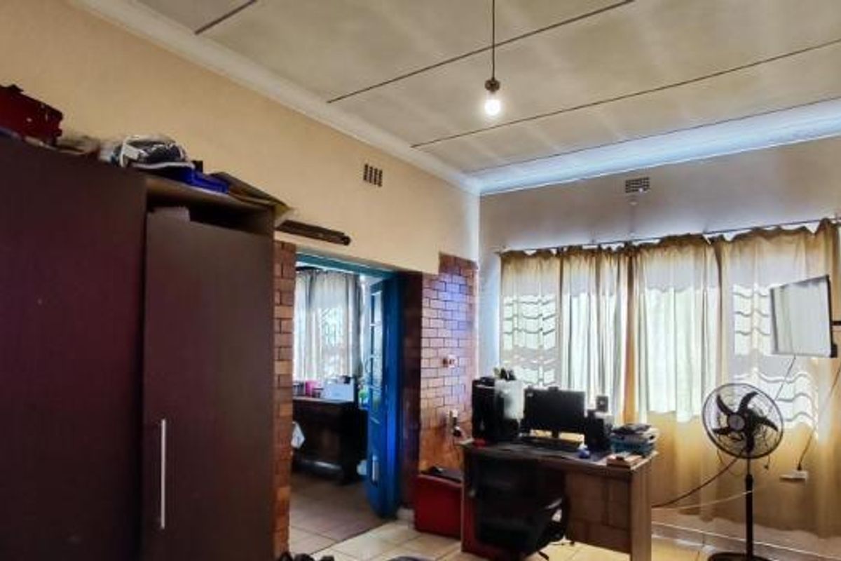 A bedroom featuring exposed brick accents, built-in cabinetry, and a tiled ceiling, offering potential for cosmetic updates to improve the overall aesthetic.