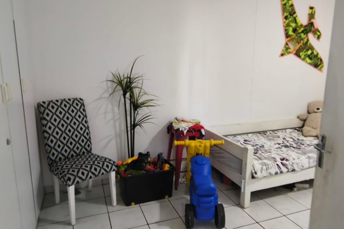 A bedroom featuring built-in cupboards and tiled flooring, currently utilized as a child's room.