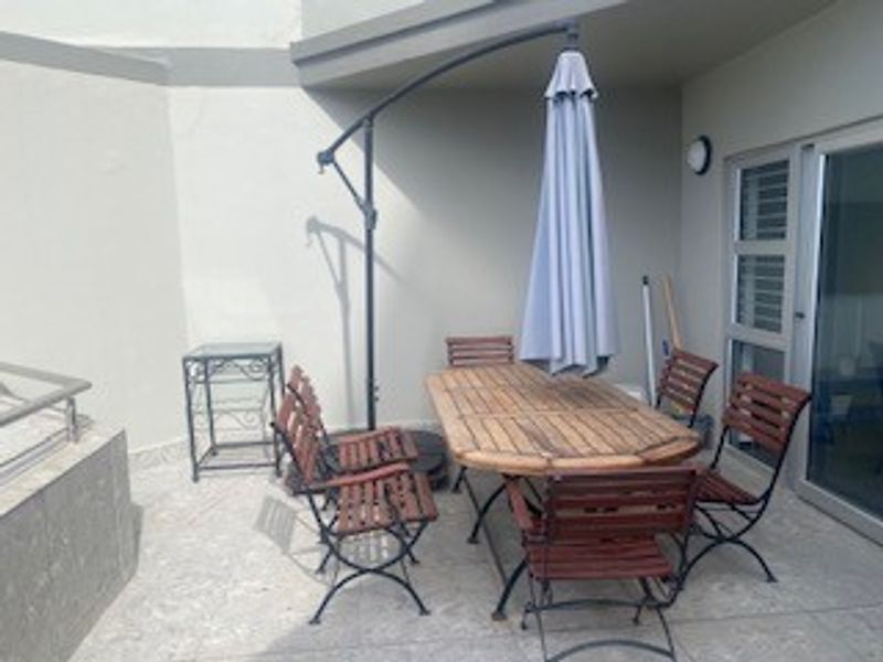 A covered outdoor patio area featuring tiled flooring and direct access to the interior through a sliding glass door.