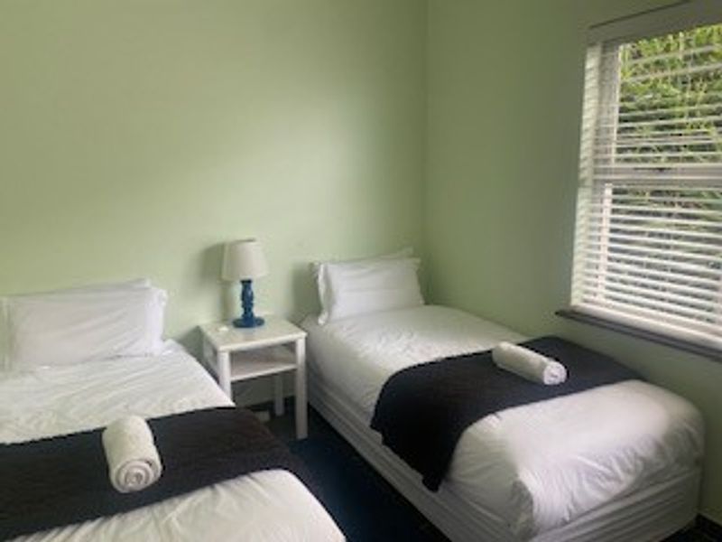 A functional bedroom featuring light green walls and a window fitted with venetian blinds.