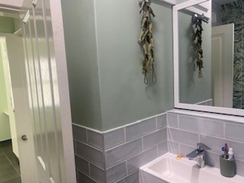 A well-maintained bathroom featuring a modern vanity basin with a mixer tap, subway tile splashback, and a wall-mounted mirror.