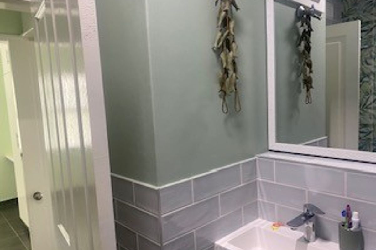 A well-maintained bathroom featuring a modern vanity basin with a mixer tap, subway tile splashback, and a wall-mounted mirror.