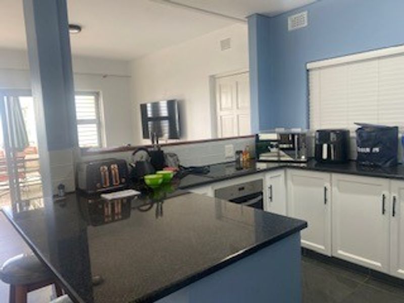 Open plan kitchen featuring granite countertops, white cabinetry, and built-in oven, seamlessly flowing into the adjacent living area.