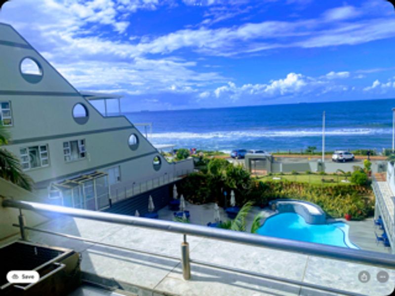 Spacious balcony featuring a built-in braai, stainless steel balustrade, and stunning elevated views overlooking the swimming pool and ocean.