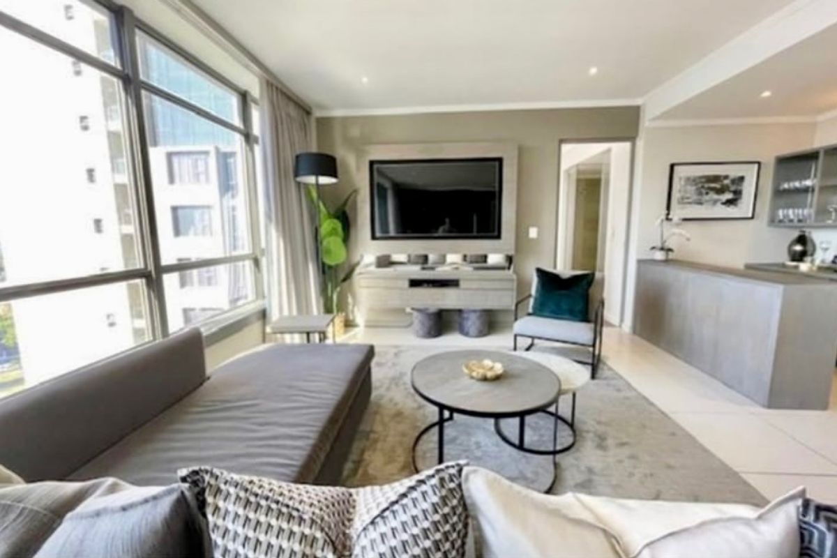 Modern open-plan living area featuring large floor-to-ceiling windows, tiled flooring, recessed lighting, and a built-in media console and bar counter.