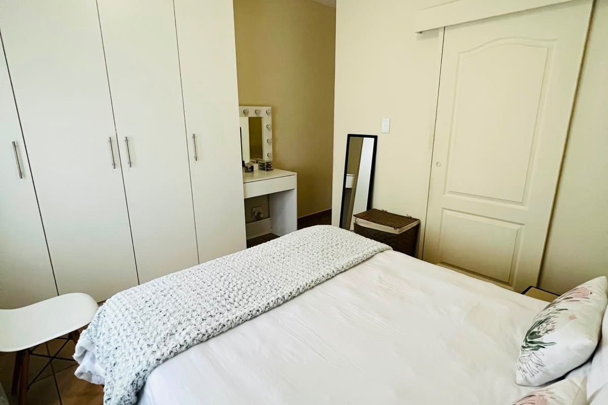 A well-maintained bedroom featuring built-in cupboards, tiled flooring, and a sliding door, offering a clean and functional living space.