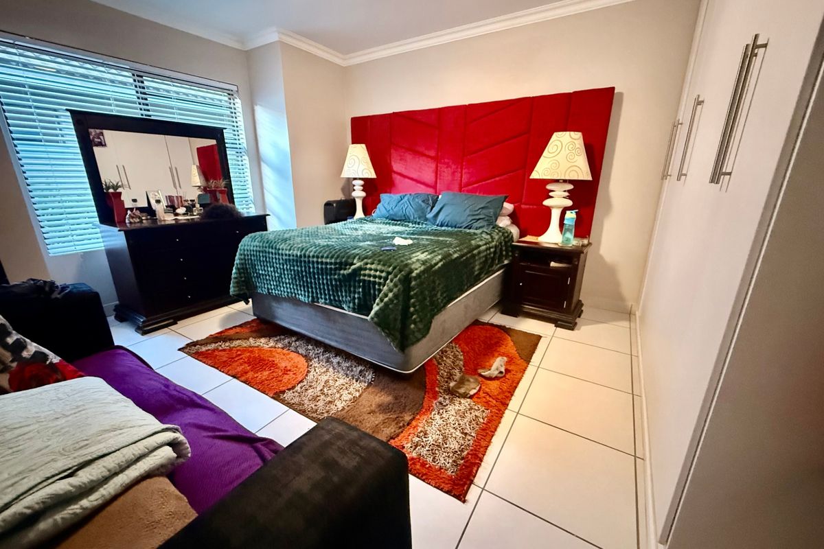 Spacious bedroom featuring tiled flooring, built-in cupboards, and venetian blinds, offering a functional layout with neutral wall finishes.