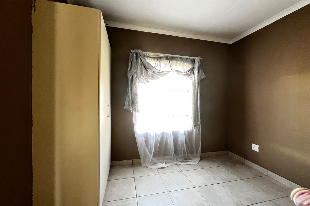 A bedroom featuring tiled flooring, a built-in wardrobe, and a window with natural light.