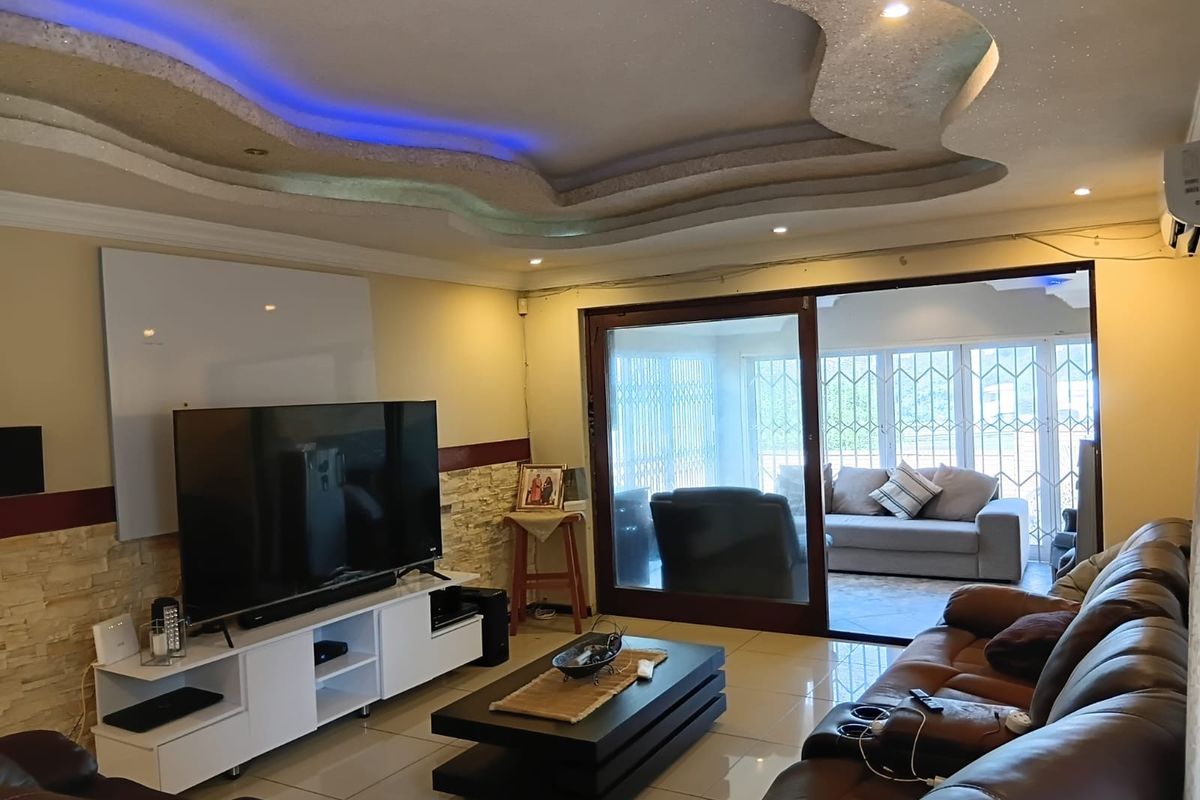 Spacious living room featuring a decorative recessed ceiling with integrated LED lighting, stone accent wall, and large sliding doors leading to an enclosed patio.
