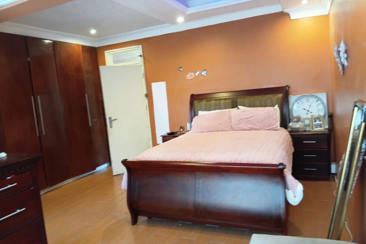 A bedroom featuring tiled flooring, built-in wooden cupboards, and a recessed ceiling with integrated lighting.