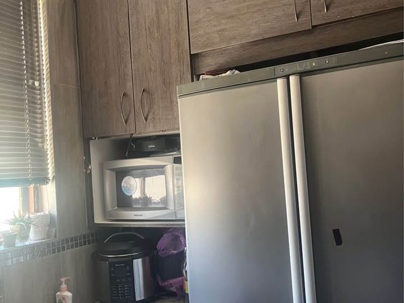 A functional kitchen area featuring wood-look cabinetry, granite countertops, a stainless steel sink, and a built-in microwave space.