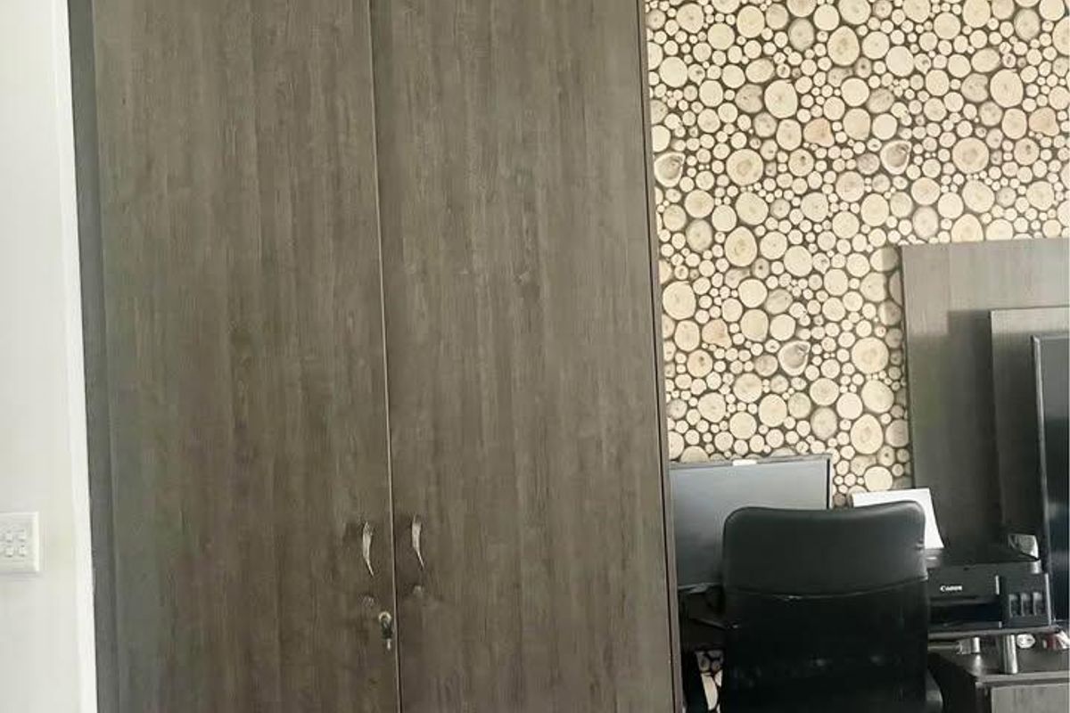 Bedroom featuring a tall built-in wardrobe with overhead storage and decorative wood-slice patterned wallpaper.