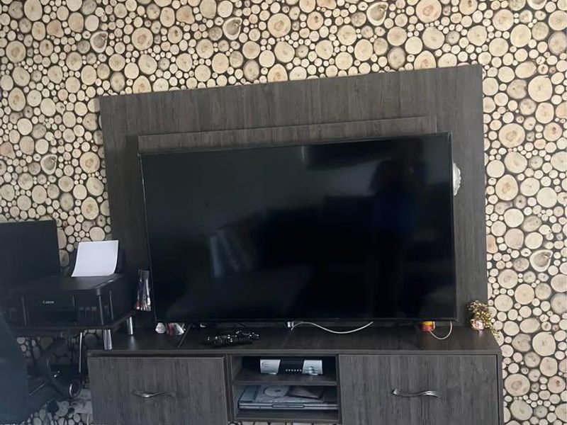 Living room area featuring a wall-mounted media console and decorative wood-slice wall finish.
