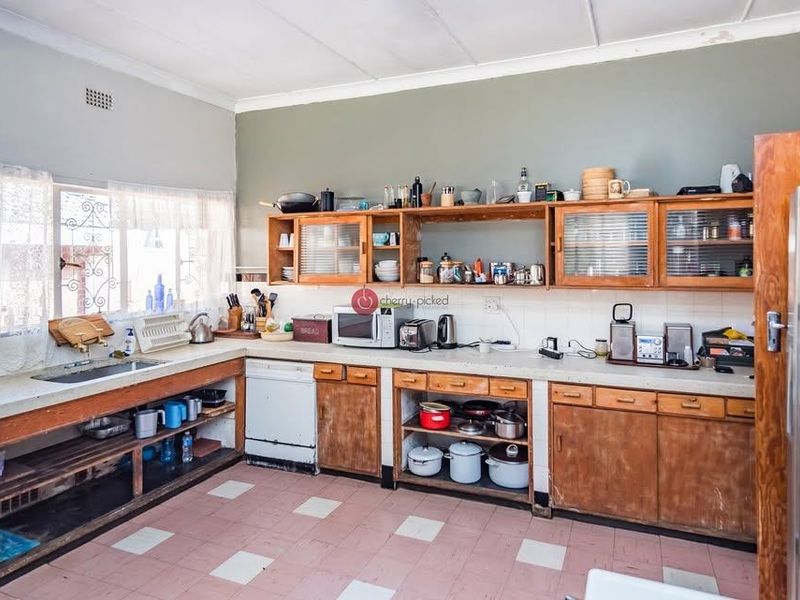 A dated kitchen featuring original wooden cabinetry, laminate countertops, and tiled flooring, offering significant potential for a modern renovation and layout update.