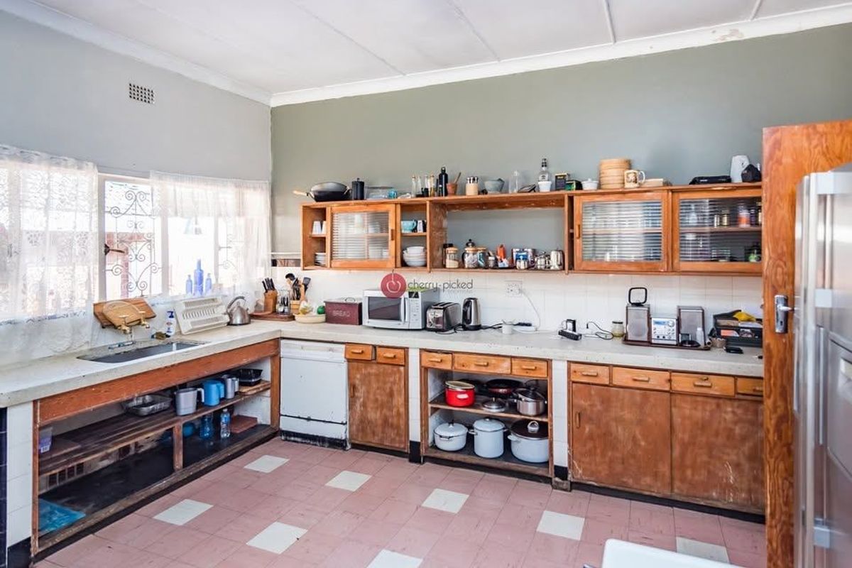 A dated kitchen featuring original wooden cabinetry, laminate countertops, and tiled flooring, offering significant potential for a modern renovation and layout update.