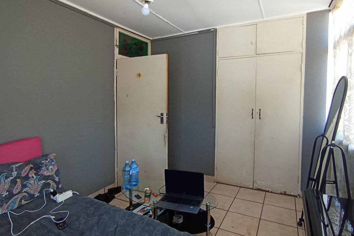 A bedroom featuring tiled flooring and built-in cupboards, requiring some cosmetic updates to improve the overall finish and appeal.
