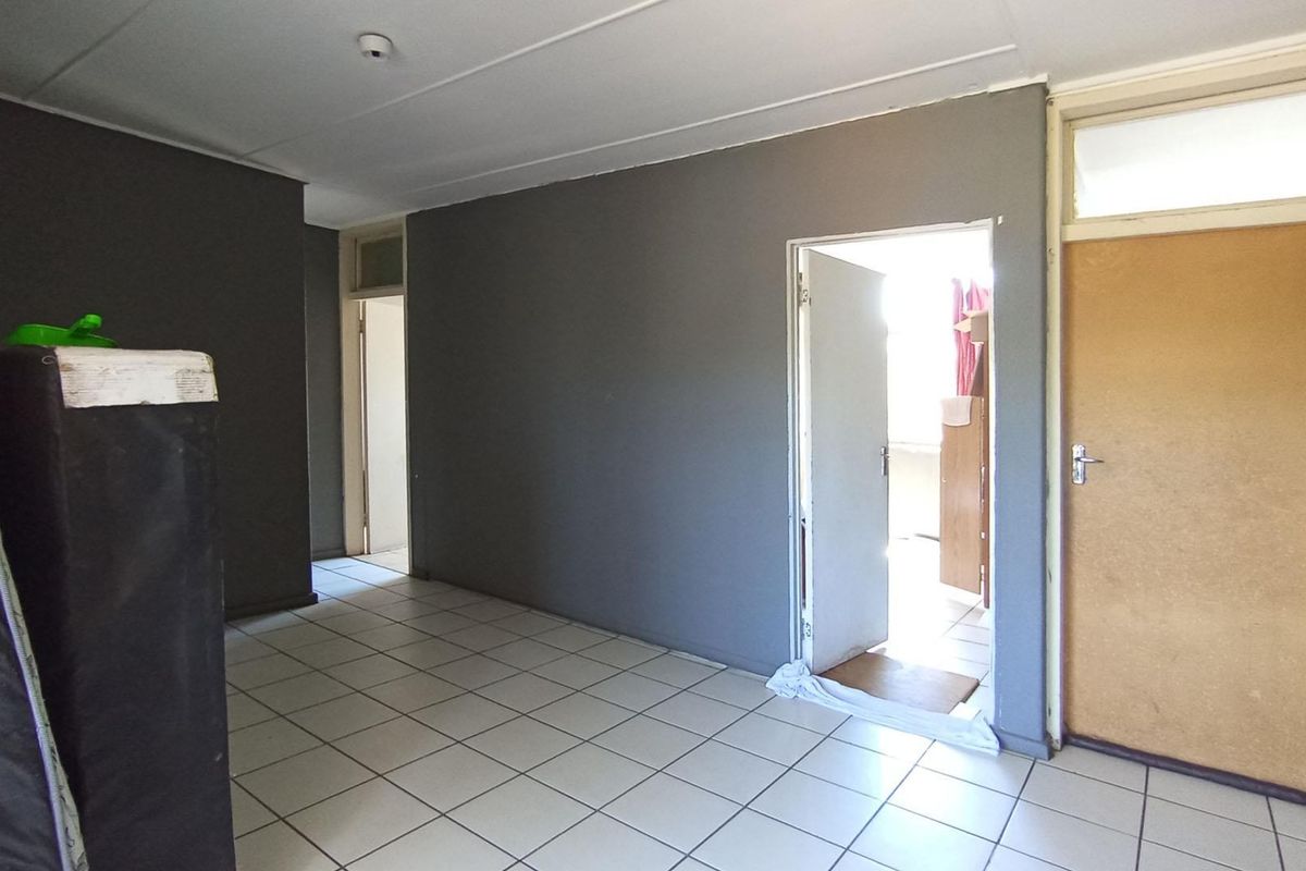 An empty living area featuring tiled flooring and neutral grey walls, providing a blank canvas for interior design and renovation.