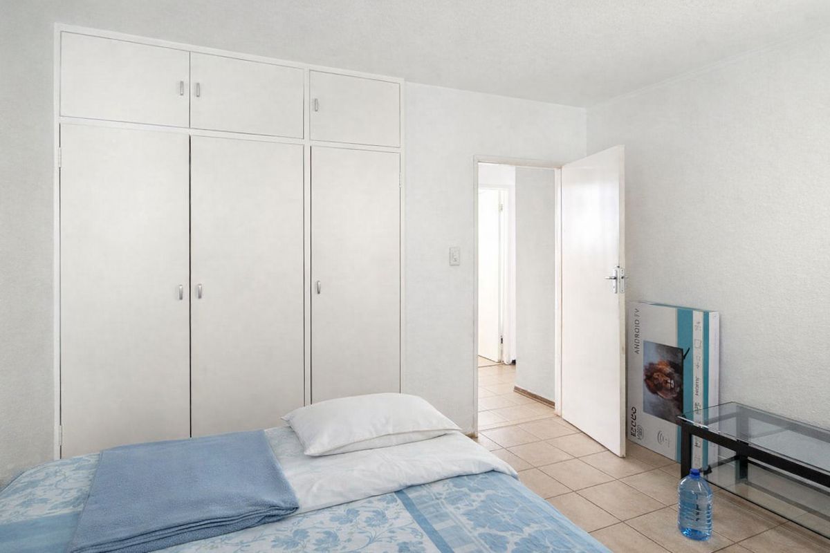 A bedroom featuring built-in cupboards and tiled flooring, providing a functional and neutral space.