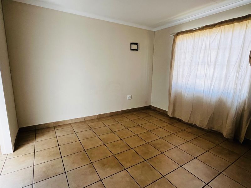 An empty bedroom featuring neutral wall finishes and ceramic floor tiles, providing a blank canvas for interior design.