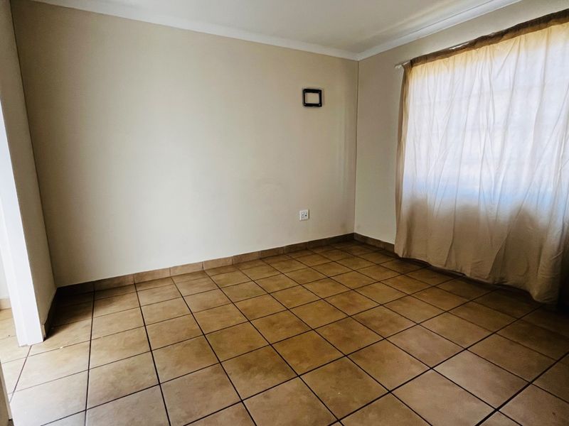 A vacant bedroom featuring neutral walls, tiled flooring, and a coved ceiling, offering a blank canvas for personalization.