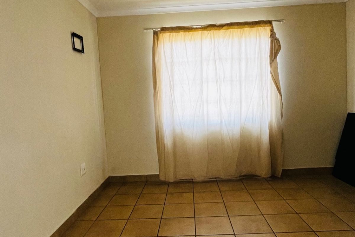 A simple, empty bedroom featuring neutral walls and tiled flooring, providing a blank canvas for personalization.