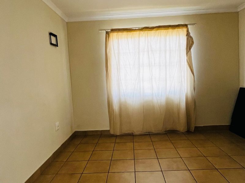 A simple, empty bedroom featuring neutral walls and tiled flooring, providing a blank canvas for personalization.