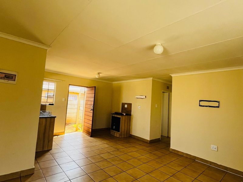 An open-plan living and kitchen area featuring tiled flooring, built-in cabinetry, and direct access to the exterior.