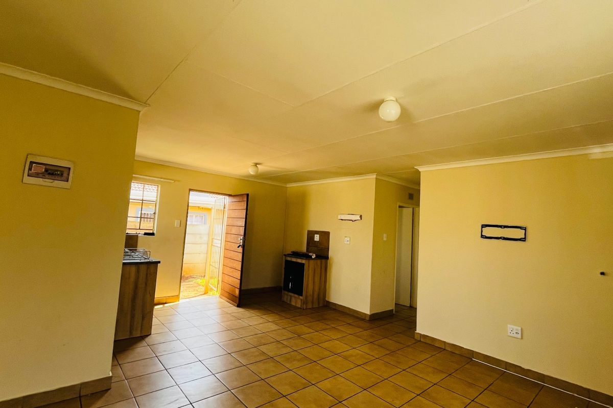 An open-plan living and kitchen area featuring tiled flooring, built-in cabinetry, and direct access to the exterior.