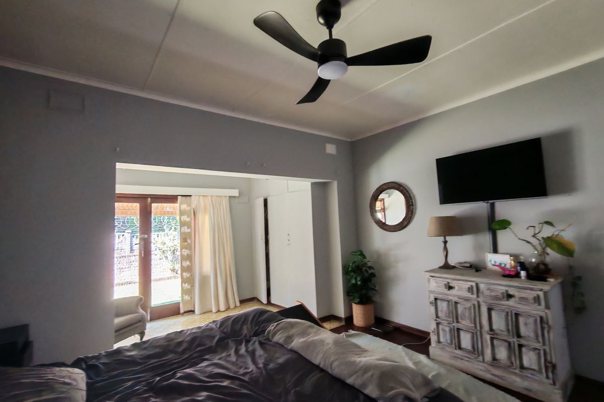 Spacious bedroom featuring a modern ceiling fan, built-in cupboards, and direct access to an outdoor area through double doors.