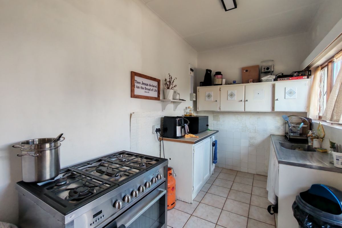 A functional kitchen featuring a gas stove, built-in cabinetry, and tiled flooring, offering a practical layout with potential for cosmetic updates.