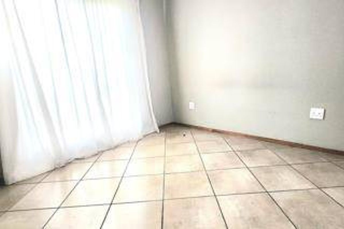 An empty living area featuring neutral tiled flooring and standard electrical fixtures, providing a blank canvas for interior design.