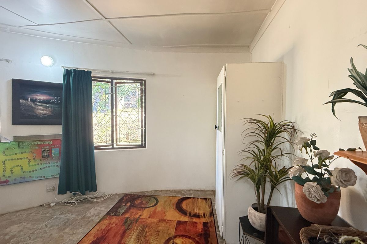 A bedroom featuring tiled flooring, built-in cupboard storage, and security bars on the windows.
