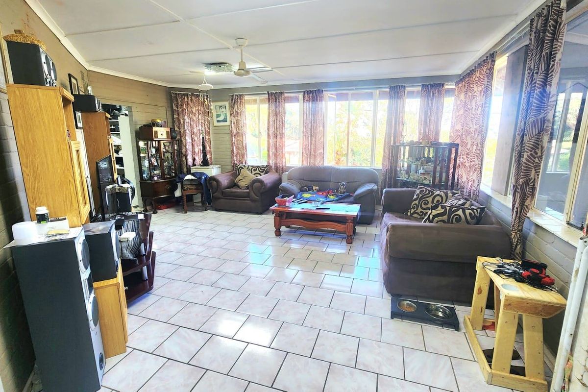 Spacious living area featuring tiled flooring, ceiling fans, and large windows that provide ample natural light.