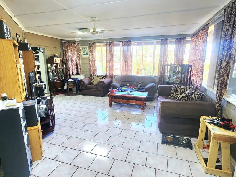 Spacious living area featuring tiled flooring, ceiling fans, and large windows that provide ample natural light.