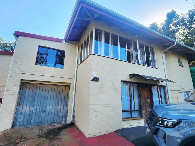 Front elevation of a townhouse featuring a single garage, brick facade, and large windows with aluminium frames.