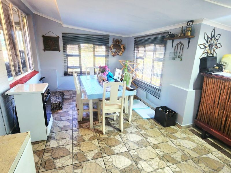 Open-plan living and dining area featuring tiled flooring, large windows with venetian blinds, and a coved ceiling, offering a functional space for daily living.