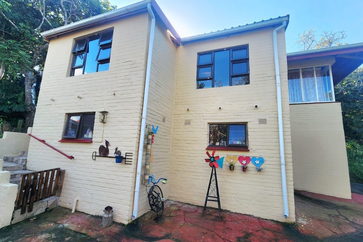 Rear exterior view of the townhouse featuring a painted brick facade, aluminium windows, and a paved courtyard area with external staircase access.