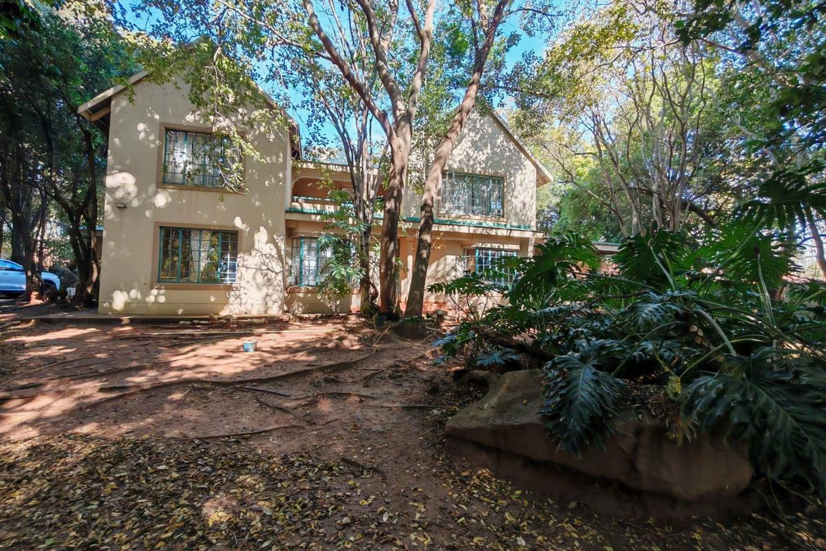 A view of the rear two-story building facade surrounded by mature trees and a natural garden setting.