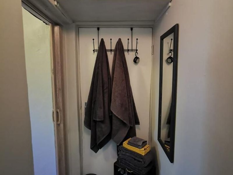 A functional hallway space featuring built-in overhead shelving and a doorway leading to an adjacent room.