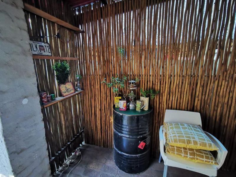 A rustic outdoor patio area featuring a natural reed screen wall, brick masonry, and built-in shelving, offering a cozy and textured outdoor living space.