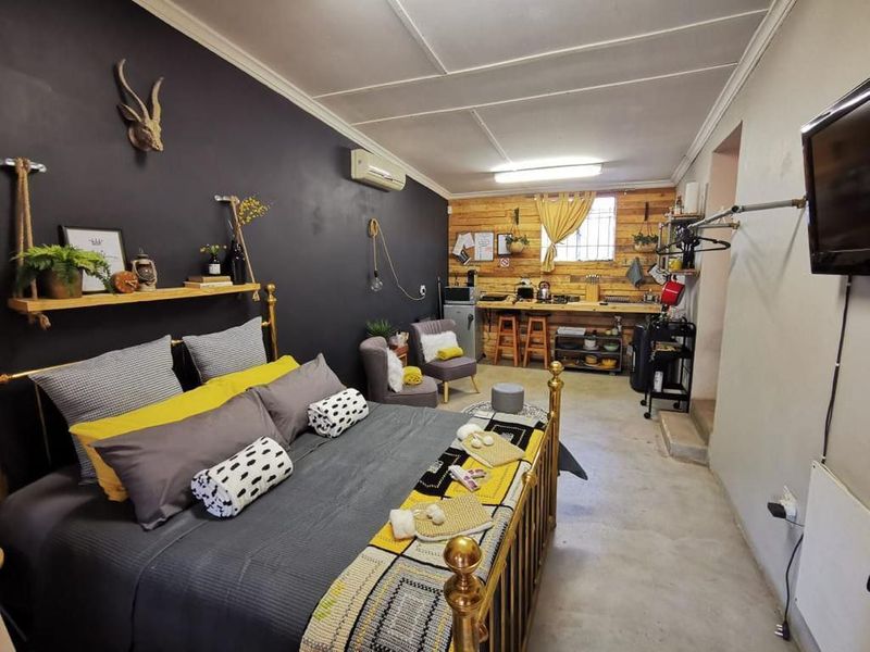 Open-plan studio space featuring a kitchenette with timber cladding, concrete flooring, and a split-system air conditioner.