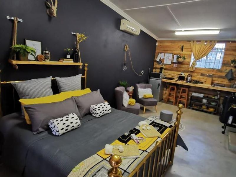 Open-plan studio space featuring a sleeping area, kitchenette with timber finishes, concrete floors, and a split-system air conditioner.