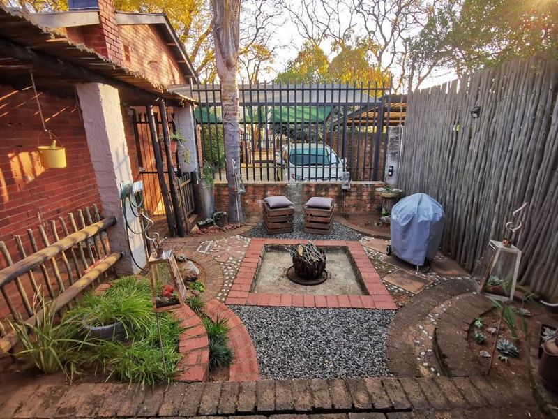 A private rear courtyard featuring a built-in brick fire pit, gravel landscaping, and secure perimeter fencing, providing a cozy outdoor entertainment space.