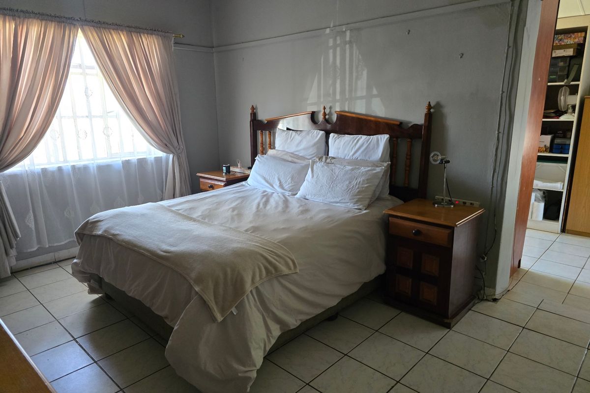 A bedroom featuring tiled flooring, a picture rail, and security bars on the window, requiring minor cosmetic updates to wall finishes.
