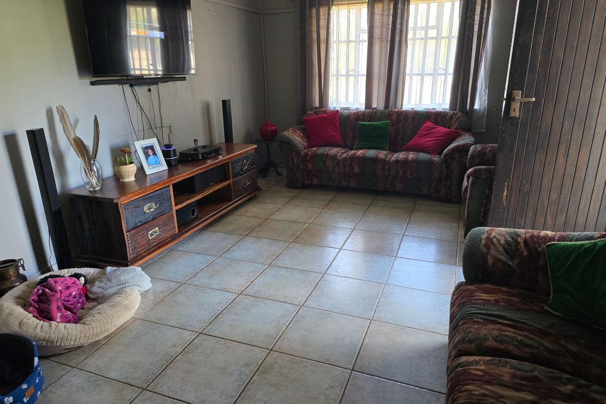A living room featuring tiled flooring, security bars on the windows, and a timber door, providing a functional and lived-in space.