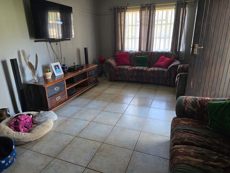 A living room featuring tiled flooring, security bars on the windows, and a timber door, providing a functional and lived-in space.